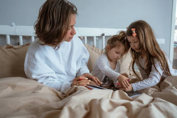 Mom and two daughters draw in bed — Stock Photo, Image