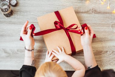 Kadının el el yapımı sarma kağıdı kırmızı kurdele ile sunmak.