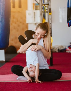 Anne ve kızı birlikte farklı egzersizler yapıyorlar.