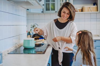 Küçük tatlı bir kız ve annesi mutfaktalar.