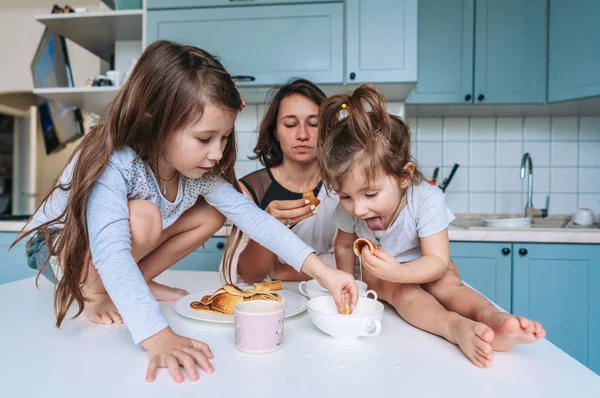 Mom and two daughters eat pancakes — Stock Photo, Image