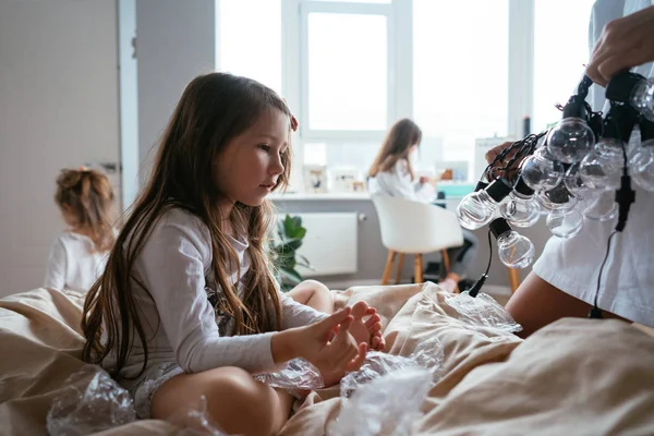 Sorrindo menina sentada em uma cama grande — Fotografia de Stock