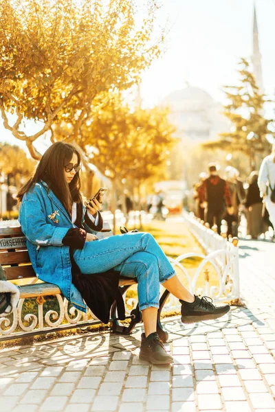 Una ragazza è seduta su una panchina — Foto Stock