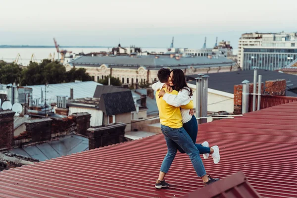 Amar pareja joven está de pie en el techo de la casa. —  Fotos de Stock