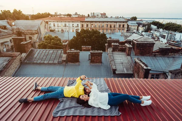 Красивий хлопець і молода дівчина лежать на даху і тримають шарфони . — стокове фото