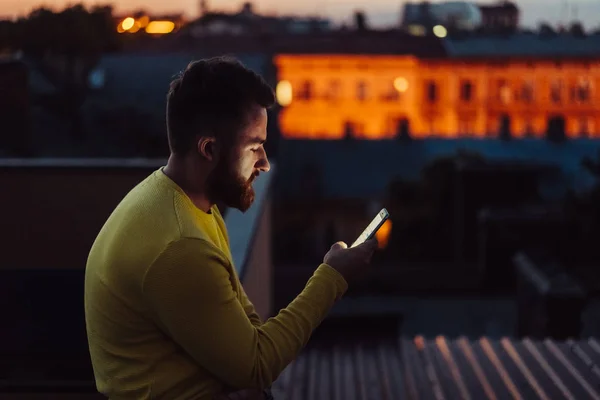 El joven está de pie en el techo de la casa y leyendo el mensaje . —  Fotos de Stock