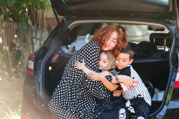 Mulher feliz sentada com seus filhos no carro — Fotografia de Stock