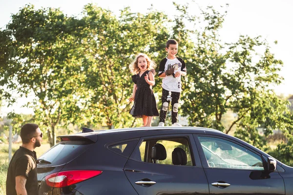 Dos niños de pie en el techo de un coche — Foto de Stock