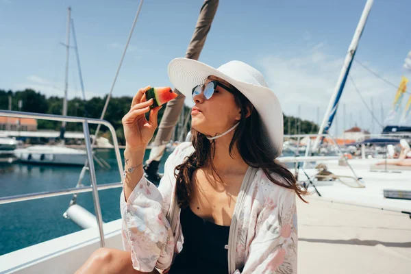 Nő ül a fedélzeten, és eszik egy görögdinnye. — Stock Fotó