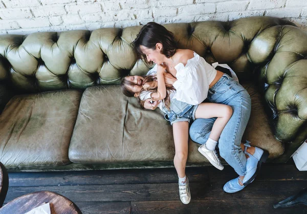 Mamá y su niña se divierten en el sofá — Foto de Stock
