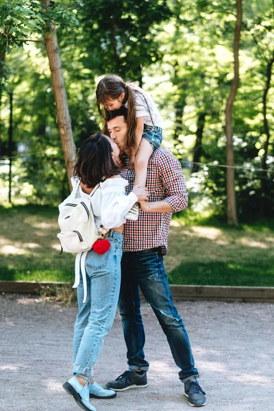 Happy young parents kiss in the park.