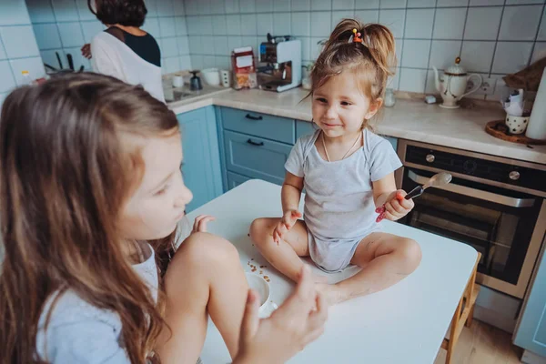 Két kislány ül a konyhában az asztalon.. — Stock Fotó