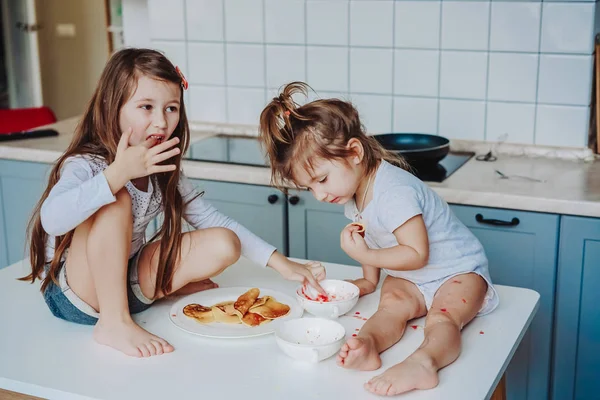 Duas meninas na cozinha sentadas na mesa. — Fotografia de Stock