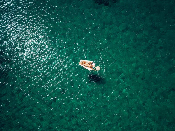 Deux jeunes belles femmes caucasiennes allongées sur un matelas dans de l'eau calme et azur — Photo