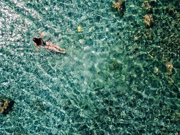 Menina em um maiô preto nada no mar . — Fotografia de Stock