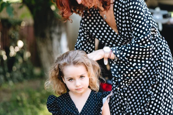 Eine junge Mutter kämmt ihren kleinen Töchtern die Haare — Stockfoto