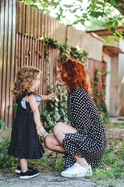Young mother and her little daughter at the fence — Stock Photo, Image