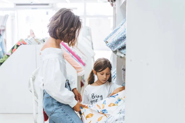 Mom and daughter in the fabric store choose fabric — Stock Photo, Image