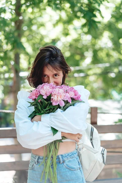 Mladá žena s kyticí růžové pivoňky — Stock fotografie