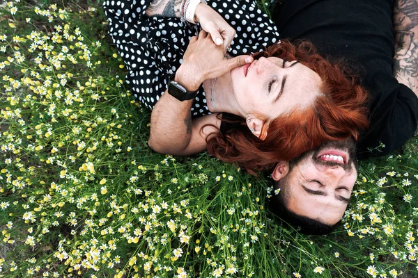 Jeune couple se couche sur le terrain avec des marguerites . — Photo
