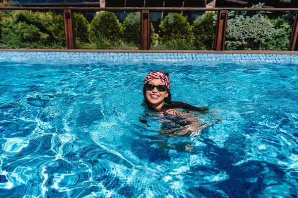 Beautiful teenage girl relaxing in pool water — Stock Photo, Image