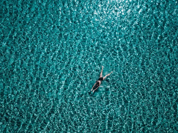 Jeune fille en maillot de bain noir nage dans la mer . — Photo
