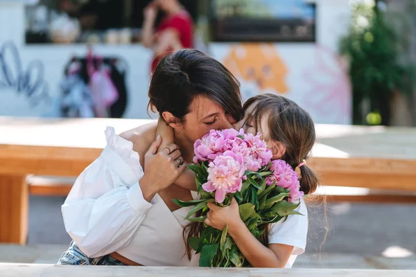 Mãe e filha beijando buquês de peônias — Fotografia de Stock