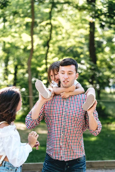 Glückliche junge Familie spaziert durch den Park — Stockfoto
