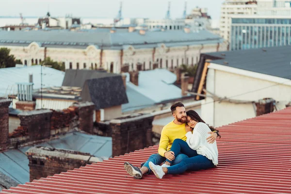 Amar pareja joven está sentado en el techo de la casa. —  Fotos de Stock