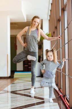 Anne ve kızı birlikte farklı egzersizler yapıyorlar.