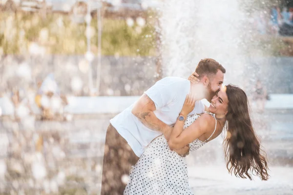 英俊的男孩和美丽的女孩亲吻喷泉的背景 — 图库照片