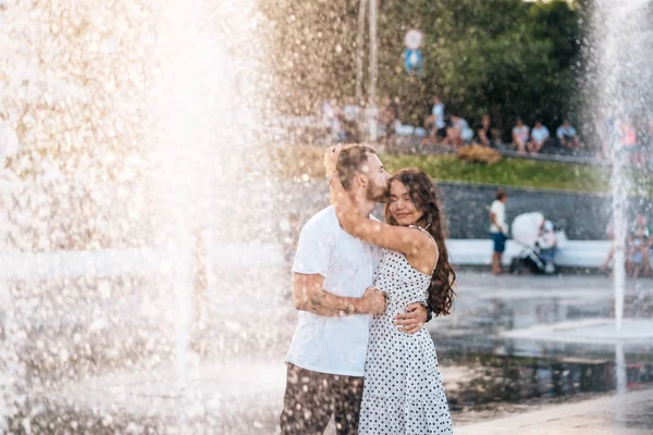 Handsome guy kisses the beautiful girl on a background of a fountain — Stock Photo, Image