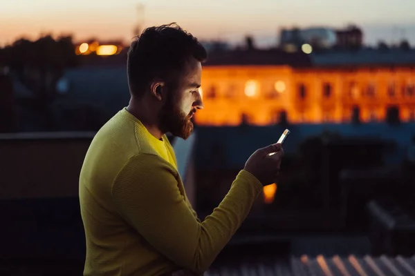 Молодий чоловік стоїть на даху будинку і читає повідомлення . — стокове фото