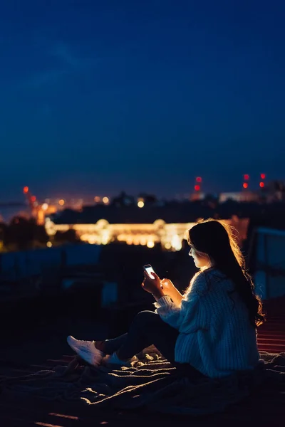 Молодая девушка сидит ночью на крыше дома. Прекрасный вечер — стоковое фото