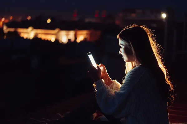 Молодая девушка сидит ночью на крыше дома. Прекрасный вечер — стоковое фото