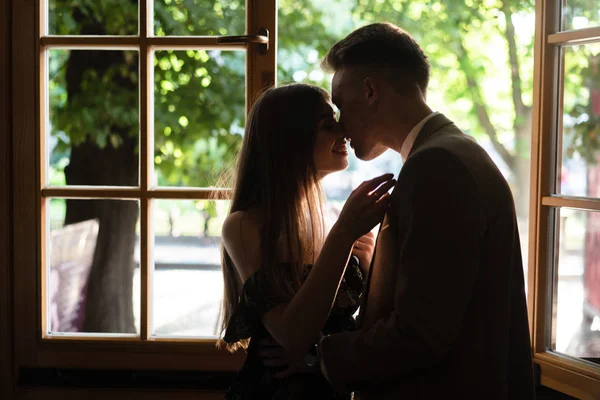 Jovem casal apaixonado de pé junto à janela — Fotografia de Stock