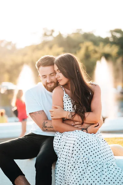 Handsome guy hugs a beautiful girl on a background of a fountain — Stock Photo, Image