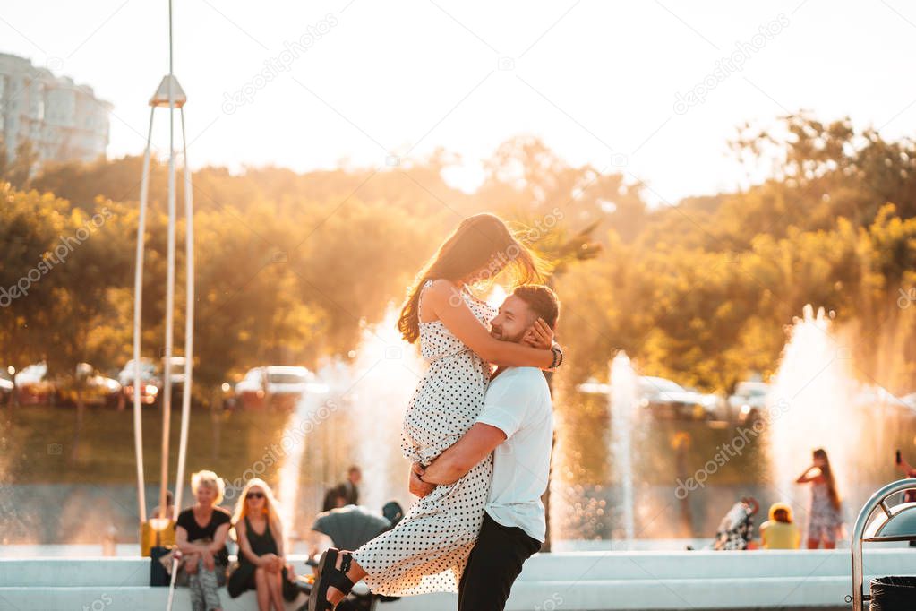 Handsome guy twists a beautiful girl on a background of a fountain