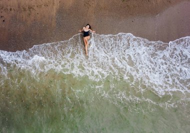 Kumsalda, dalgaların yanında genç Asyalı kadın..