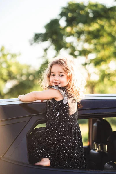 Una bambina è in piedi sulla porta della macchina — Foto Stock