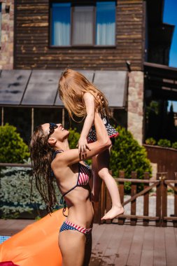 Anne kızı onun kollarında tutar.