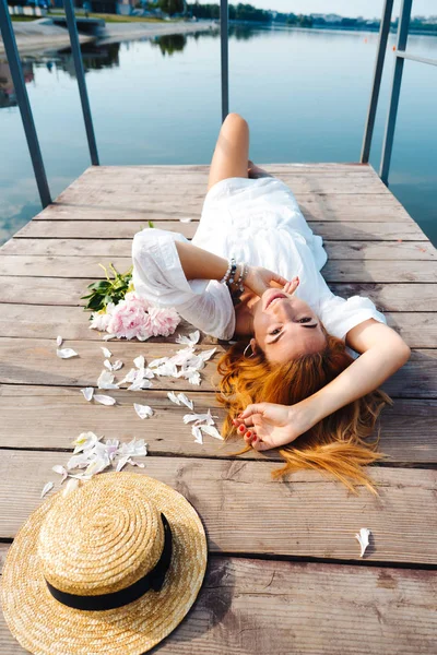 Attractive young hipster woman in white dress lies on the wooden floor. — Stock Photo, Image