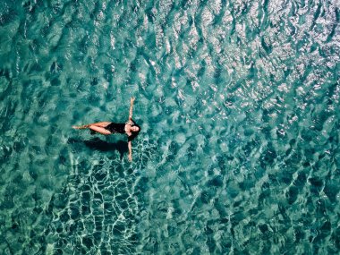 Bir siyah mayo genç kız denizde yüzüyor.