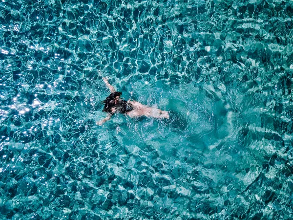 Młoda dziewczyna w czarny strój kąpielowy pływa w morzu. — Zdjęcie stockowe