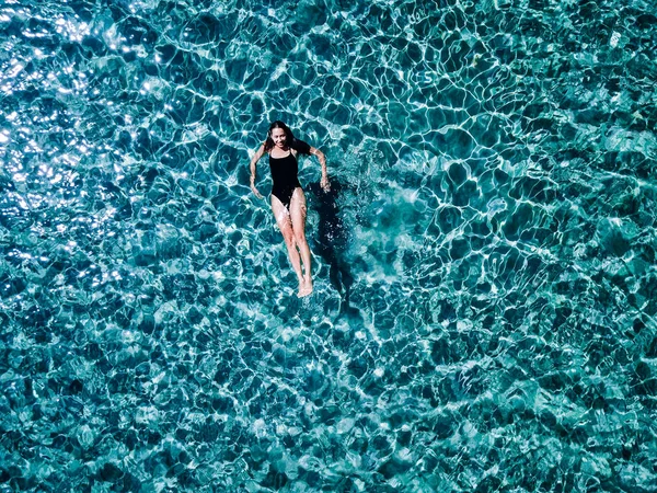 Młoda dziewczyna w czarny strój kąpielowy pływa w morzu. — Zdjęcie stockowe