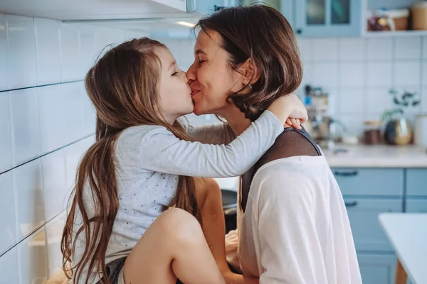 Mamma kysser sin lilla dotter i köket — Stockfoto