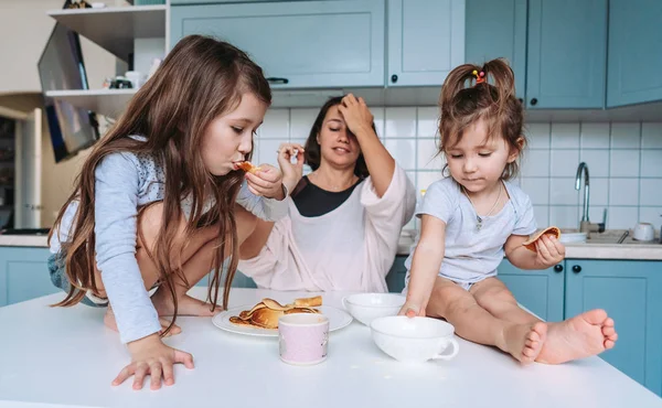 Mom and two daughters eat pancakes — Stock Photo, Image