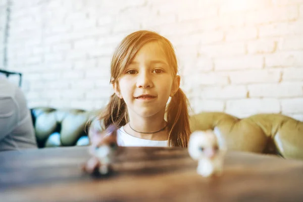 Chica jugando con pequeñas figuras sentadas en suave — Foto de Stock