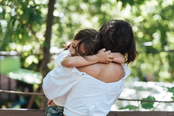 Genç Anne küçük kızı parkta hugs. — Stok fotoğraf