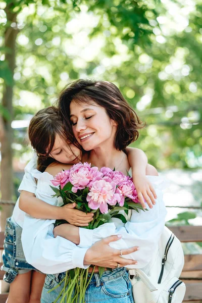 Jovem mãe com um buquê de flores está se divertindo com sua filha — Fotografia de Stock